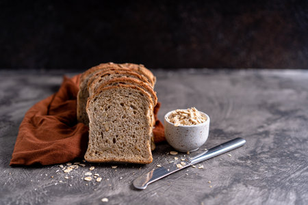 Sliced whole grain loaf bread on dark rustic wooden backgroundの写真素材
