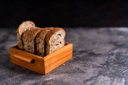 Sliced whole grain loaf bread on dark rustic wooden background