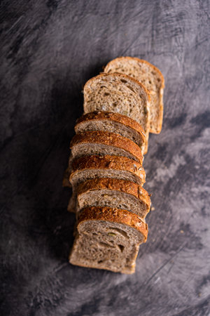 Sliced whole grain loaf bread on dark rustic wooden backgroundの写真素材