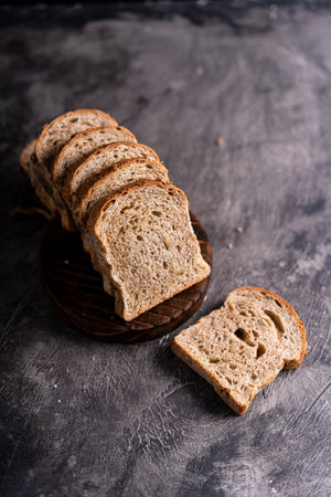 Sliced whole grain loaf bread on dark rustic wooden backgroundの写真素材