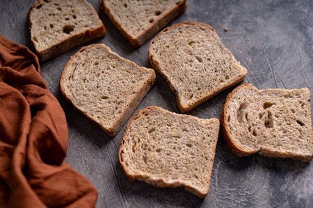 Sliced whole grain loaf bread on dark rustic wooden backgroundの写真素材