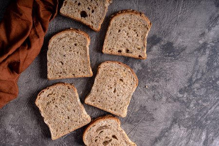 Sliced whole grain loaf bread on dark rustic wooden backgroundの写真素材