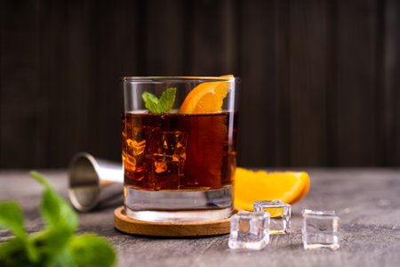 Cuba libre cocktail with orange, mint and ice on dark wooden backgroundの写真素材
