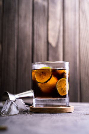Cold Cuba Libre or Long island iced tea cocktail with brown rum, cola, mint, lime, muddler, jigger and glassの写真素材