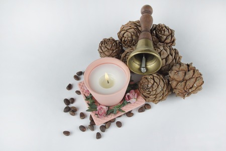 Pink candle and pine cones with nuts on a white backgroundの写真素材