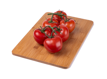 red tomatoes on a twig, lie on a wooden board, image on a white backgroundの写真素材