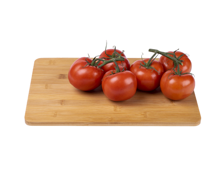 red tomatoes on a twig, lie on a wooden board, image on a white backgroundの写真素材