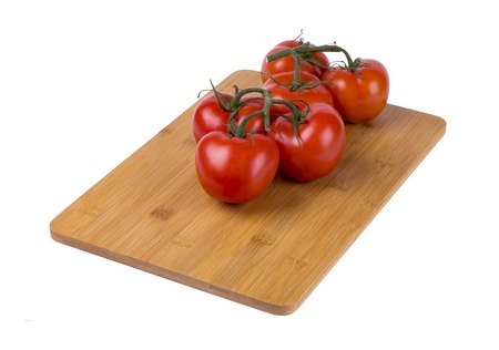 red tomatoes on a twig, lie on a wooden board, image on a white backgroundの写真素材