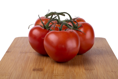 red tomatoes on a twig, lie on a wooden board, image on a white backgroundの写真素材