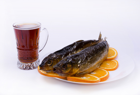 beer and fish on orange slices laid out on a white plateの写真素材