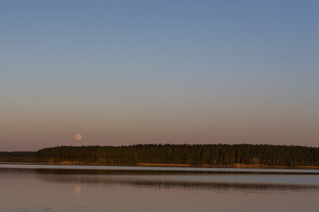 the moon hangs over the lakeの写真素材