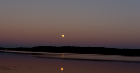the moon hangs over the lakeの写真素材