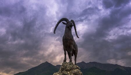 Russia, Arshan June 2019, a sculpture of a mountain goat in the resort of Arshan in Buryatia on the background of the Sayan mountainsの写真素材