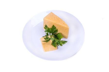 piece of cheese on a white plate with a sprig of parsley, top view on a white isolated backgroundの写真素材