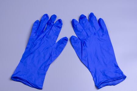two latex gloves in blue lie on a gray background, top viewの写真素材