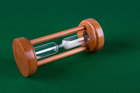 wooden hourglass lie on a green background, closeup photo, top view