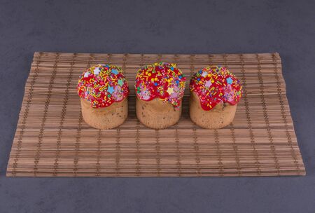 three small, tasty cupcakes with red icing on a gray background, top view