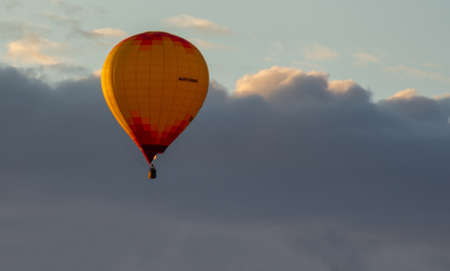 an air balloon with a basket floating in the sky, the photo was taken on a clear summer eveningの写真素材