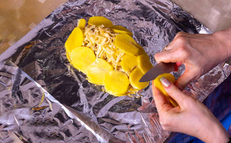 culinary meat preparation from slices of potatoes and champignons in foil, close-up photo, top viewの写真素材