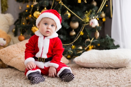 funny baby boy weared in Santa hat with golden Christmas ballの写真素材