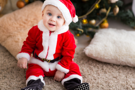 funny baby boy weared in Santa hat with golden Christmas ballの写真素材