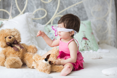 Cute girl, princess, a child in a pink dress on the white bedの写真素材