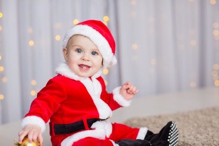 funny baby boy weared in Santa hat with golden Christmas ballの写真素材