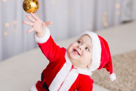 funny baby boy weared in Santa hat with golden Christmas ballの写真素材