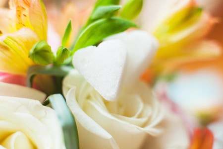 White sugar in heart shape on the background flowersの写真素材