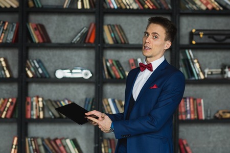 young businessman in blue suit emotional posing with tabletの写真素材