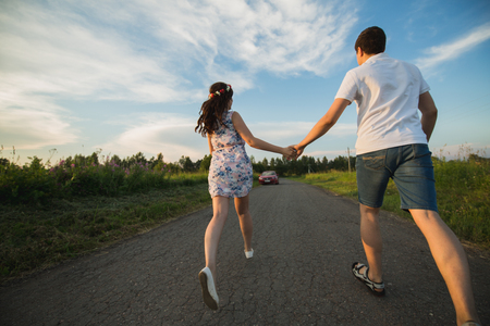 Young couple running along country road.の写真素材