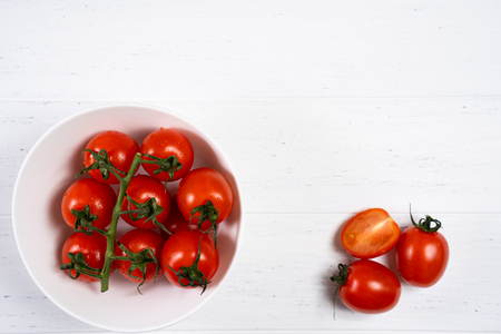 Fresh cherry tomatoes in a plate on a white wood background.の写真素材