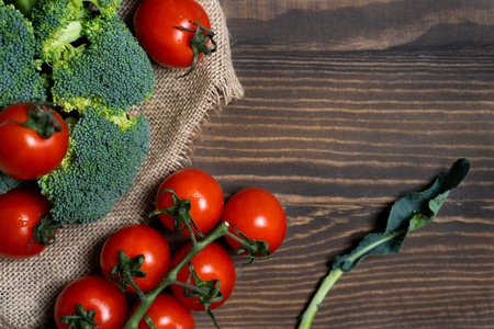 Fresh broccoli and cherry tomatoes on a dark wood background.の写真素材