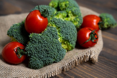Fresh broccoli and cherry tomatoes on a dark wood background.の写真素材
