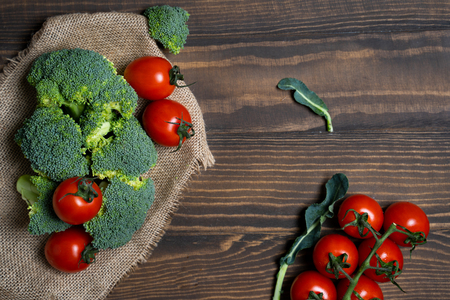 Fresh broccoli and cherry tomatoes on a dark wood background.の写真素材