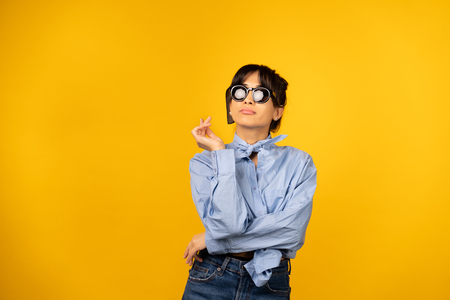 Young girl with in sunglasses posing for a photo on yellow background.の写真素材