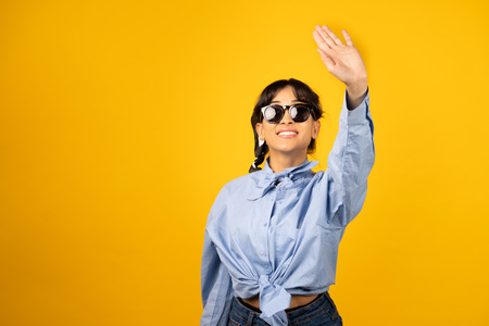 Young girl with in sunglasses posing for a photo on yellow background.の写真素材
