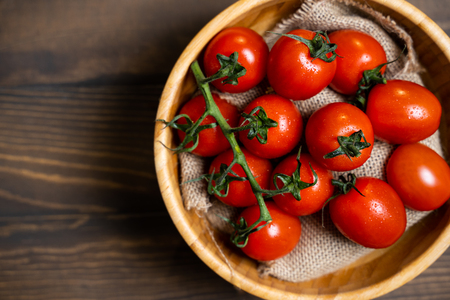 Fresh cherry tomatoes in a plate on a dark wood background.の写真素材