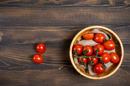 Fresh cherry tomatoes in a plate on a dark wood background.の写真素材
