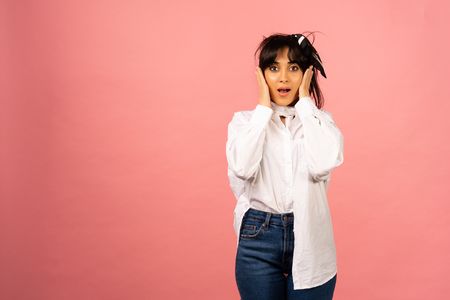 Young beautiful girl in a white shirt posing for a photo on a pink background.の写真素材