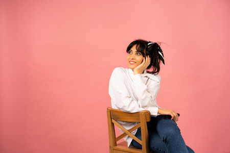 Young beautiful girl in a white shirt posing for a photo on a pink background.の写真素材