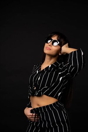 Young business girl in a black suit posing for a photo on a black background.の写真素材