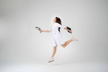 A young girl doctor or student with a phonendoscope stands on a white backgroundの写真素材