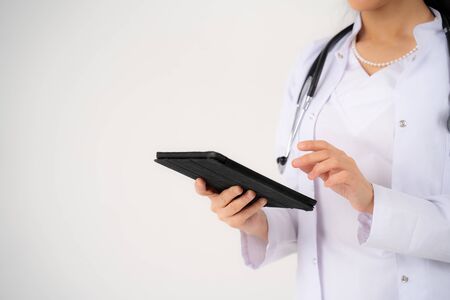 Close up of the hands and electronic tablet of a young girl doctorの写真素材