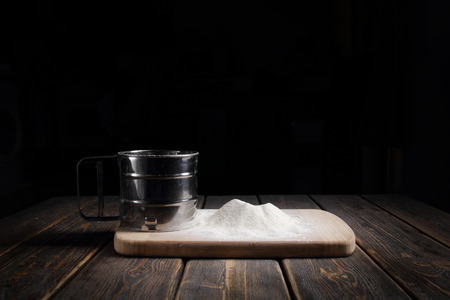 Sieve flour on wooden tableの写真素材