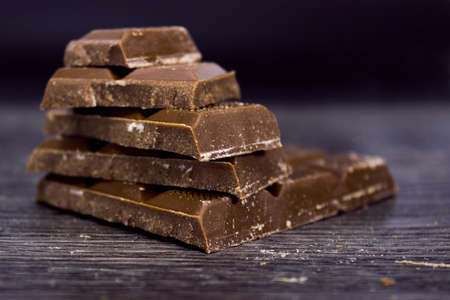 Pieces of chocolate on a black background. Chocolate bars. Close-up.
