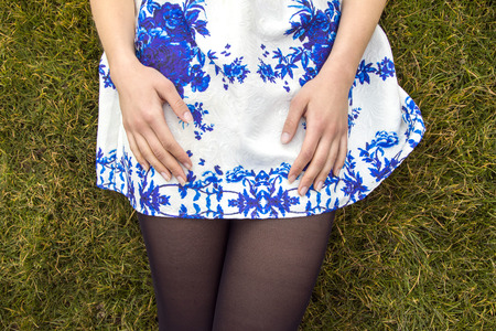 Girl in short skirt and pantyhose lying on the grassの写真素材