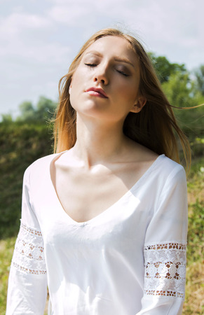 Young woman in white dress outdoor meditatingの写真素材
