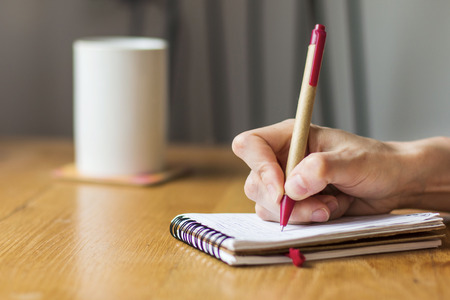 Woman at home writing and working with diaryの写真素材