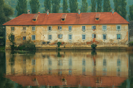 Old ruined rusty castle on the Mreznica river in Duga Resa, Croatia, reflection on waterのeditorial素材